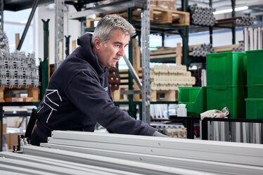 Worker hand-assembles aluminium legs of an Ecotent folding tent
