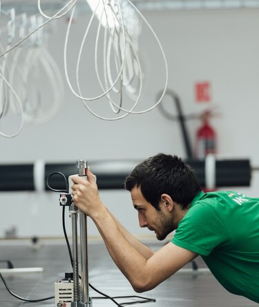 Worker testing material quality with a measuring device in folding gazebo production.